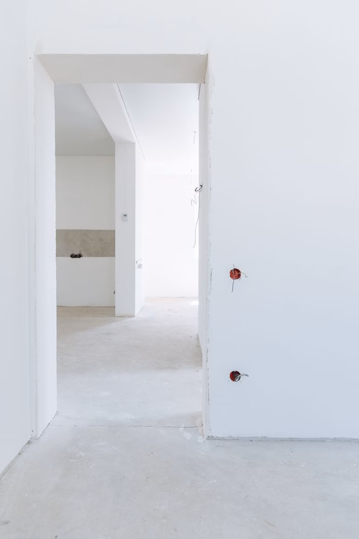 services-02 Bright unfinished room with white walls and exposed wiring, showcasing modern interior design potential.